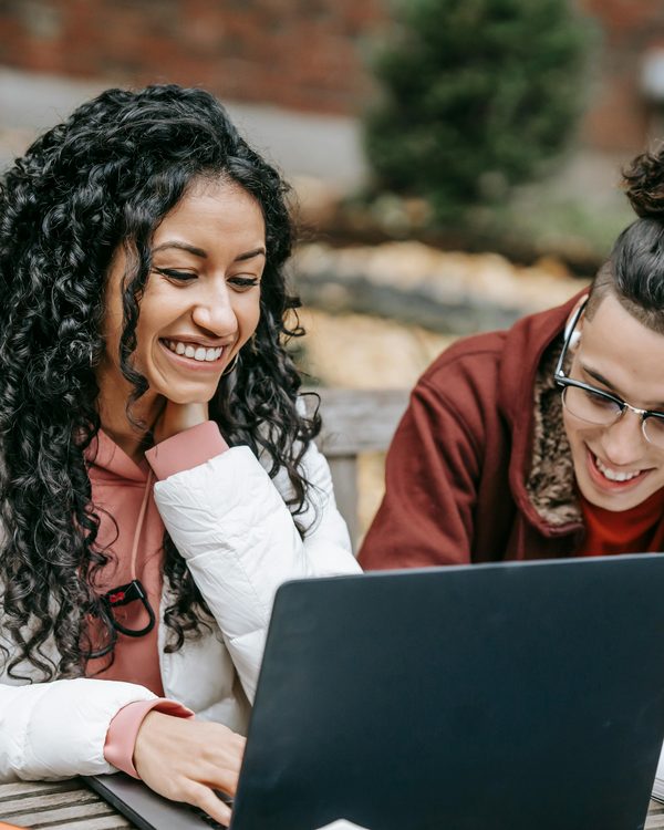 Two people smiling together while looking at a laptop screen